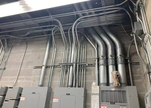 Neatly routed metal conduit running to electrical panels along a block wall