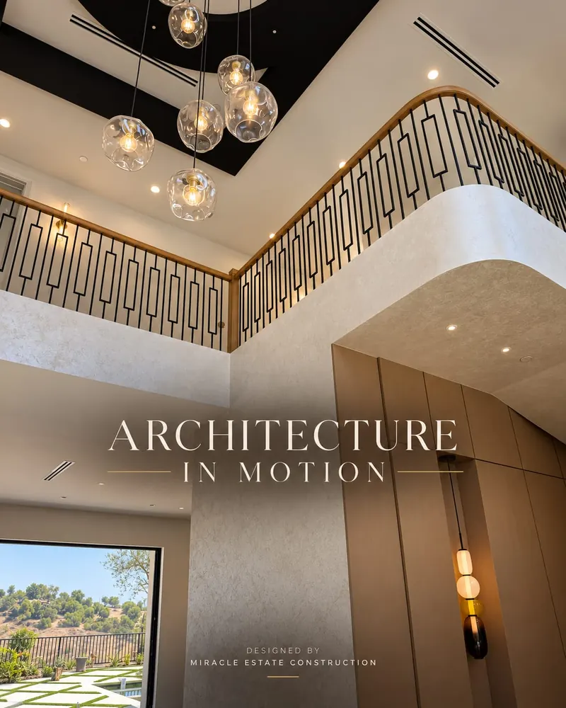 Two-story stair hall with a patterned black metal railing, glass pendant lights and a wood-paneled wall