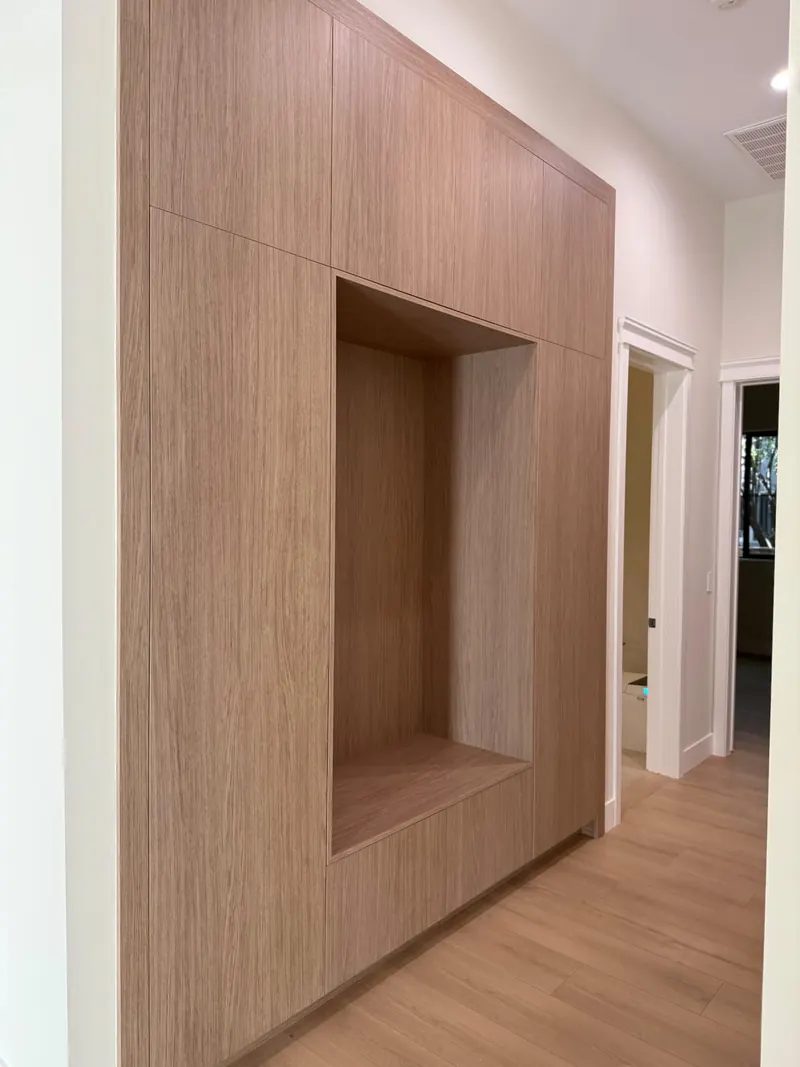 Hallway with wood-grain built-in cabinetry and a recessed niche